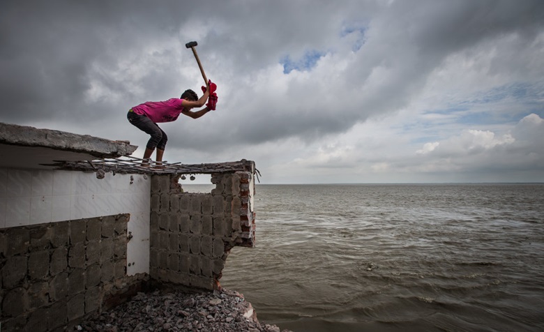 Auf diesem Foto baut Billal Hossain sein Haus ab und sammelt die letzten Steine, um sie an einen anderen Ort für einen neuen Hausbau zu verwenden. Wegen des Klimawandels wird sein Haus weggespült und er kann dort nicht bleiben.